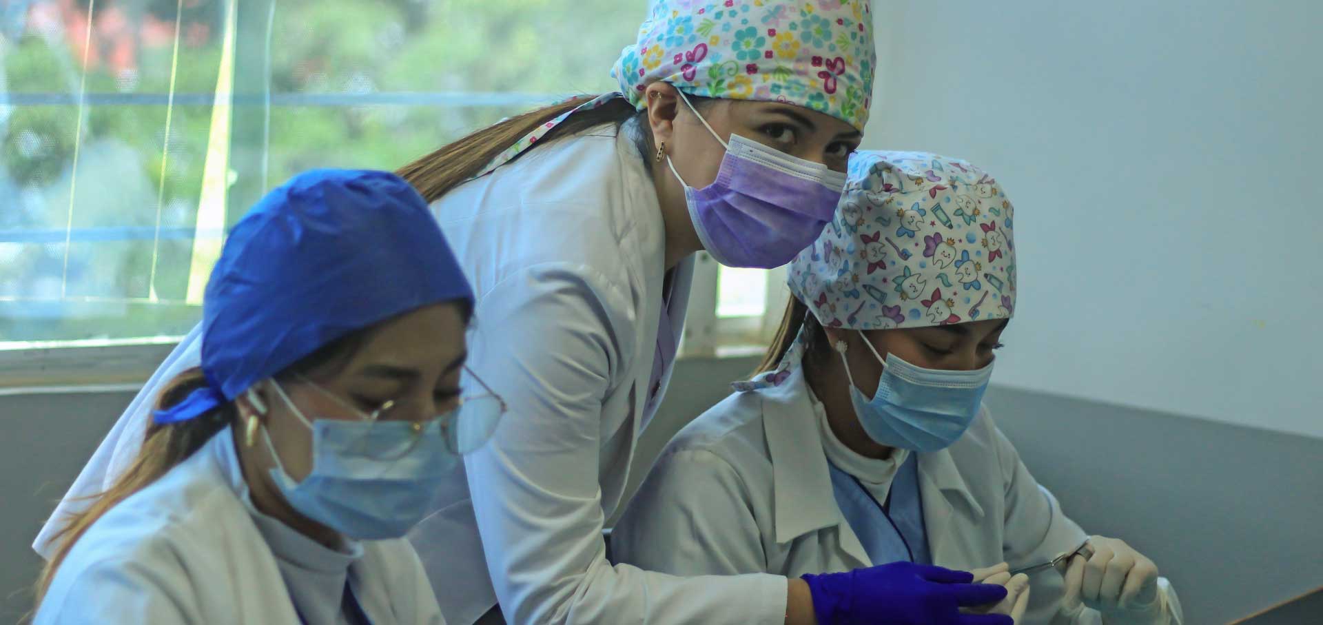 Doctora enseñándoles a dos alumnas de odontología como manejar los instrumentos